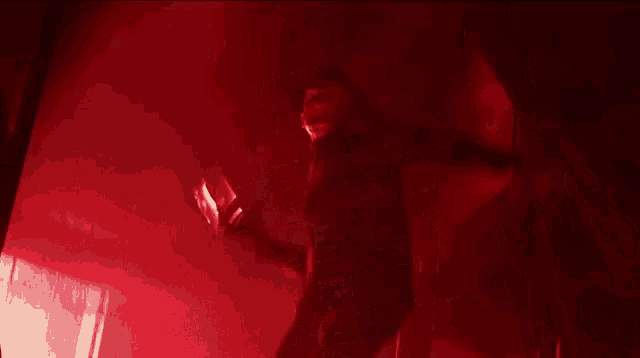 a person in a mask is standing in a dark room in a red light .