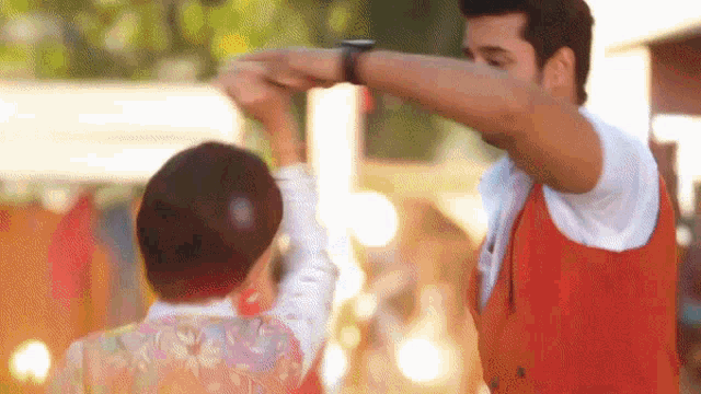 a man in a red vest is dancing with a woman in a white shirt .
