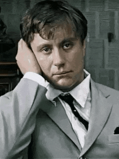 a man in a suit and tie is rubbing his ear .