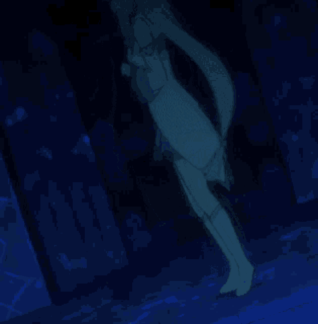 a woman in a blue dress and white boots is standing in a dark room