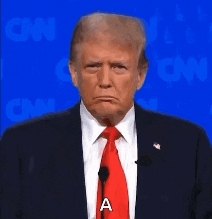 donald trump is wearing a suit and tie and making a sad face while standing in front of a microphone .
