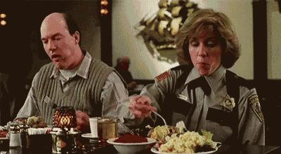 a man and a woman are sitting at a table with plates of food .