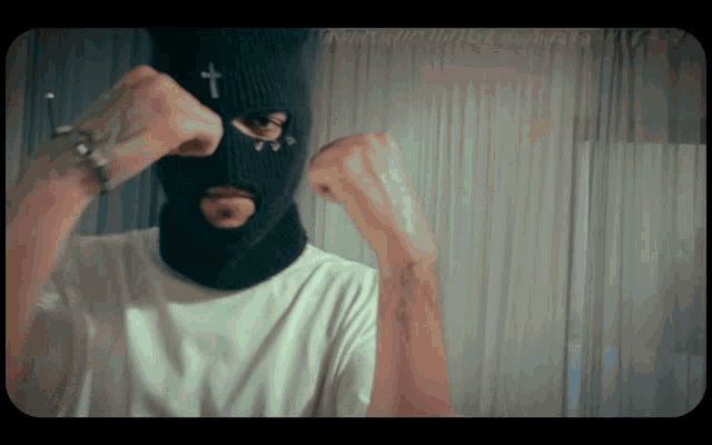 a man wearing a ski mask with a cross on the front