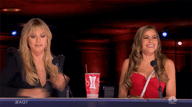 two women are sitting at a table with a sonic cup in front of them