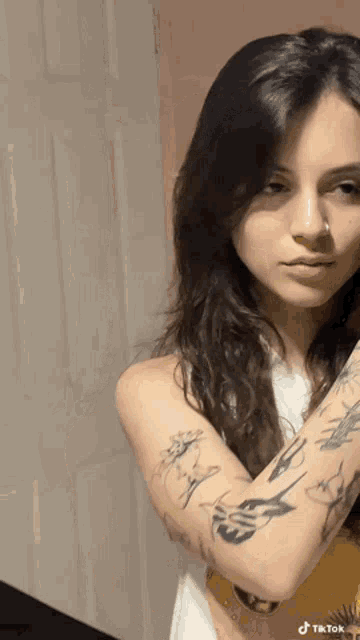 a woman with a nose ring has a tattoo on her arm that says tiktok