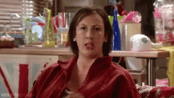 a woman in a red shirt is sitting on a couch in front of a table .