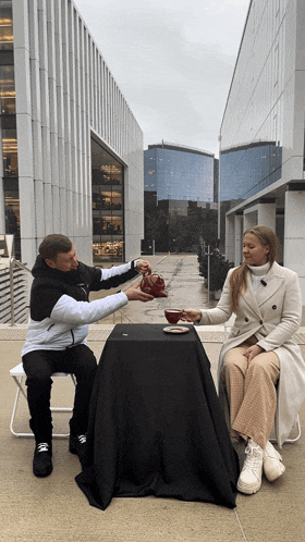 a man and a woman sit at a table with a black table cloth