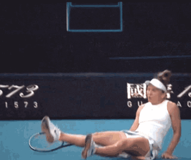 a woman is laying on the ground on a tennis court