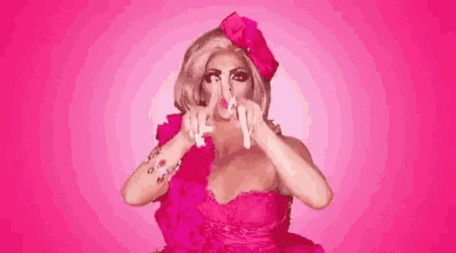a drag queen is wearing a pink dress and hat and making a funny face .