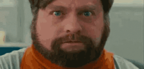a close up of a man with a beard wearing an orange scarf .
