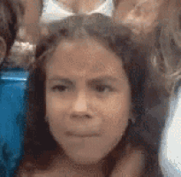 a girl is making a funny face while sitting in a crowd of people .