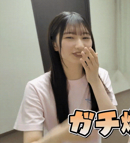 a girl in a pink shirt is covering her mouth with her hands in front of the word gacha
