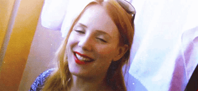a woman with red hair is smiling with her eyes closed .