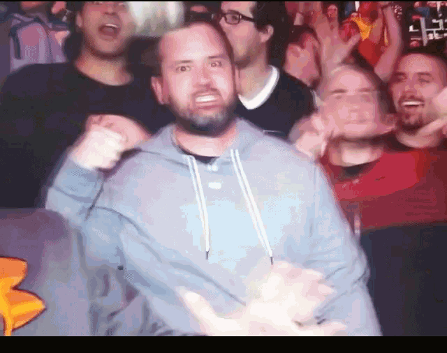 a man with a beard is standing in a crowd with his fist in the air