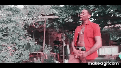 a man in a red shirt is standing in front of a tree ..