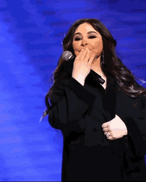 a woman singing into a microphone covering her mouth with her hand