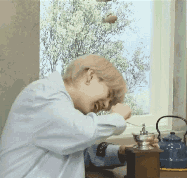a person sitting at a table with a coffee grinder in front of a window .