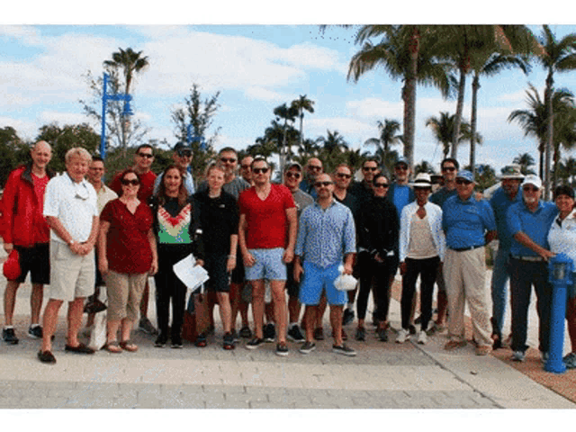 a group of people are posing for a picture with palm trees in the background