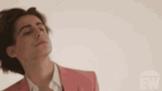 a man in a pink suit is standing in front of an ew umbrella