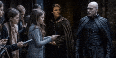 a man in a cape is talking to a group of people