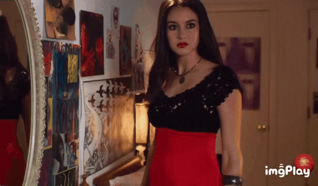 a woman in a red dress is standing in front of a mirror with imagesplay written on the bottom right
