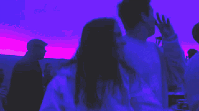 a group of people are dancing in a dark room with a purple sky in the background