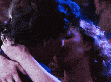 a man and woman are kissing in front of a crowd