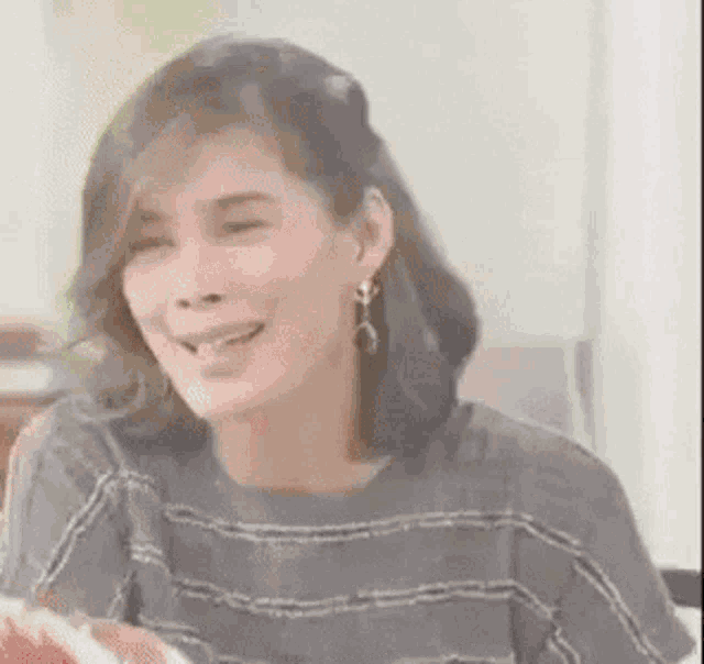 a woman is laughing while sitting at a table with her tongue hanging out .