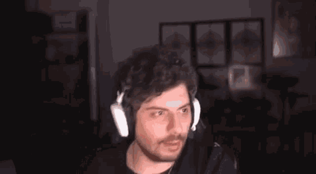 a man with a beard is wearing headphones and making a funny face .