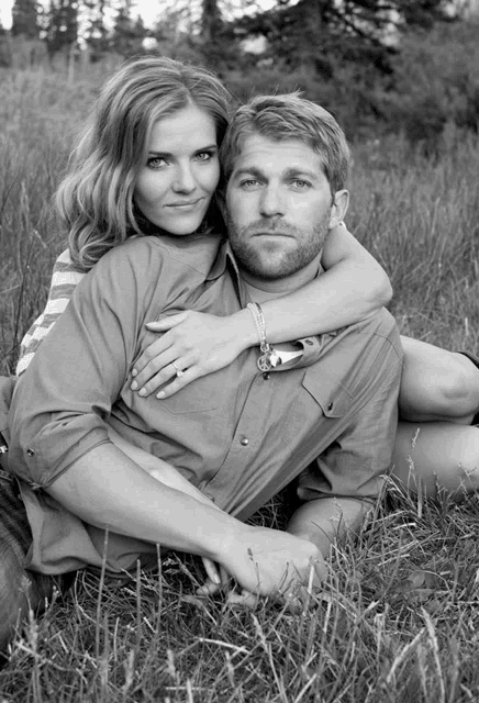 a woman sits on a man 's shoulders in a field