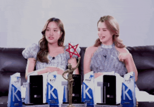 two women are sitting on a couch with a trophy in front of them that says kate