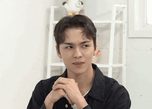 a young man is making a funny face with his hands folded