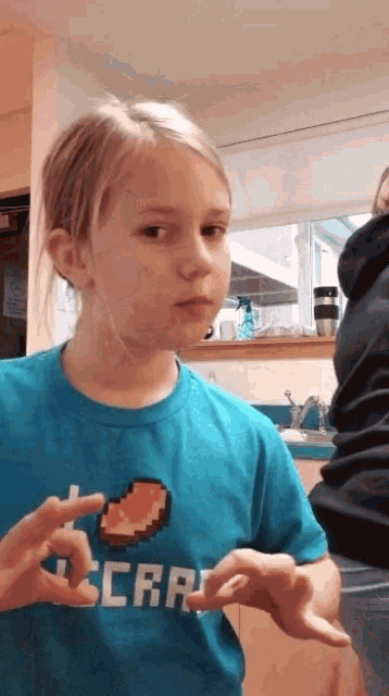 a little girl wearing a blue shirt that says minecraft on it