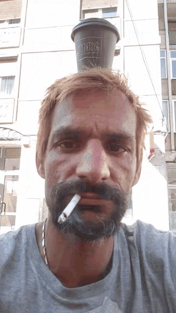 a man with a cigarette in his mouth and a coffee cup on his head that says big street
