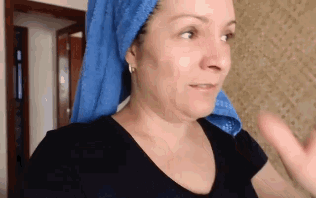 a woman with a blue towel wrapped around her head looks at the camera