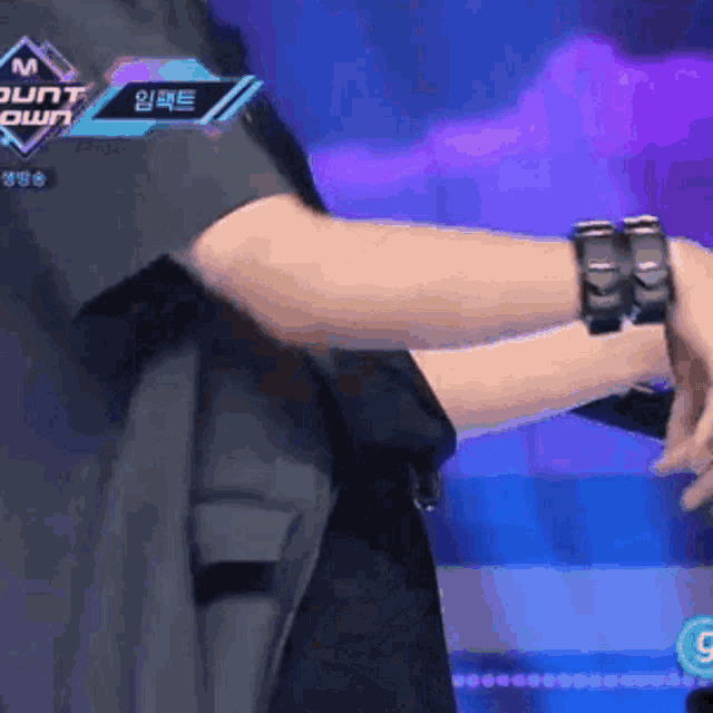 a person wearing a watch on their wrist while standing in front of a m count down sign