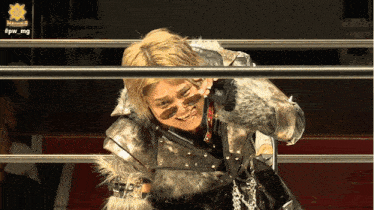 a man in a fur coat is smiling in a wrestling ring with the hashtag #pw_mg