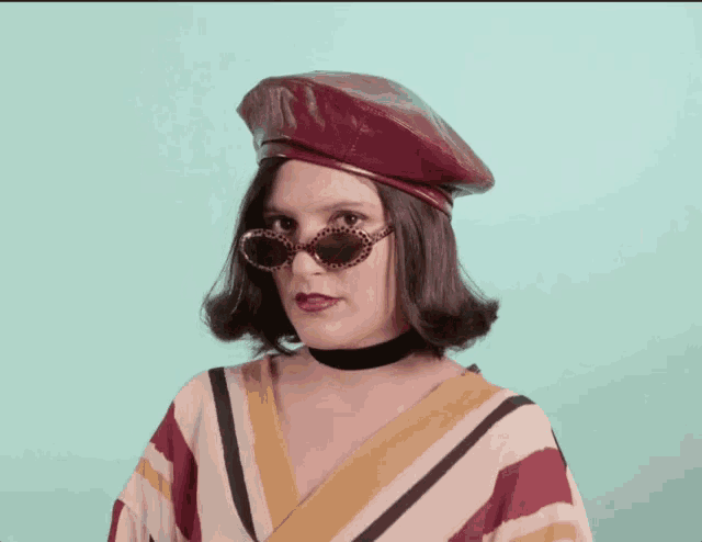 a woman wearing a red hat and sunglasses looks at the camera