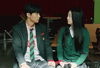 a man in a suit and tie is sitting next to a woman in a green sweater .