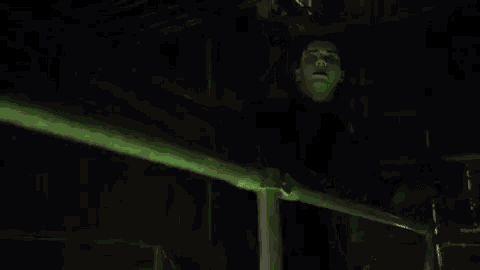 a man in a superhero costume is standing next to a green light .