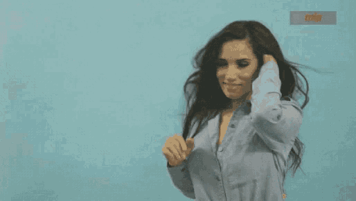 a woman in a blue shirt is smiling and looking at the camera