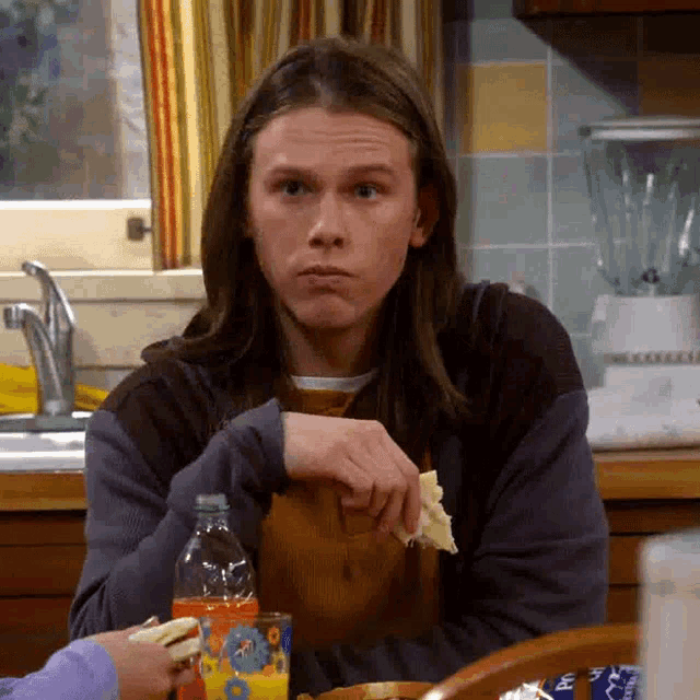 a man sitting at a table with a bottle of orange juice