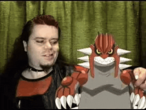 a man with red hair is holding a toy pokemon in front of a green curtain .