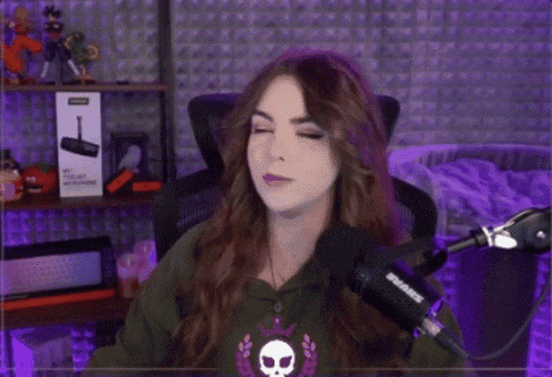 a woman is sitting in front of a microphone with her eyes closed in a purple room ..