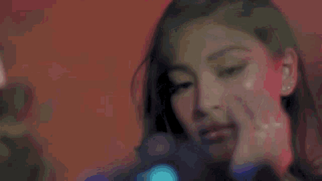 a close up of a woman 's face with a red background and a blue light behind her .