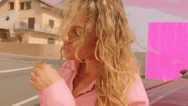 a woman in a pink shirt is eating something