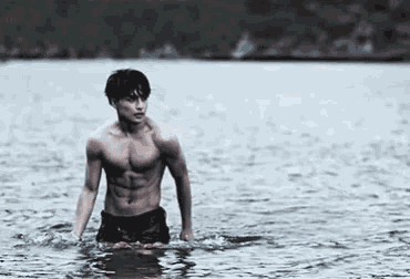 a shirtless man is standing in the water looking at the camera