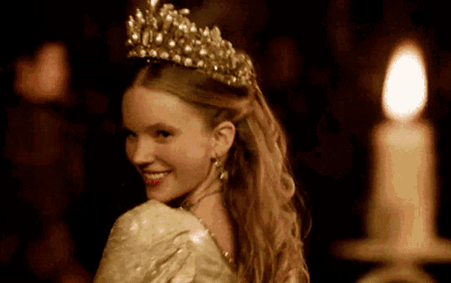 a woman with a tiara on her head is smiling in front of a candle
