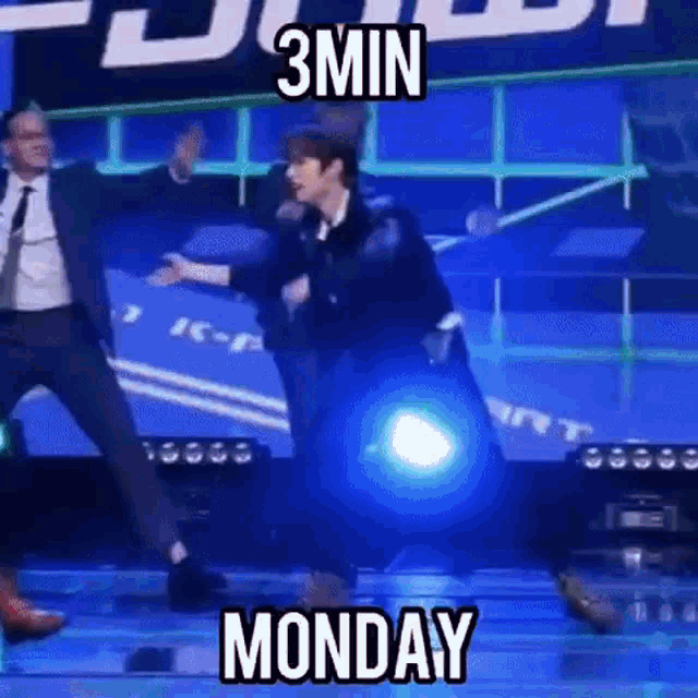 a man in a suit and tie is dancing on a stage in front of a blue background .
