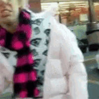 a woman wearing a white jacket and a pink and black plaid shirt